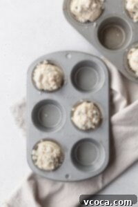 Muffin tins with blueberry muffin batter in every other muffin cup.