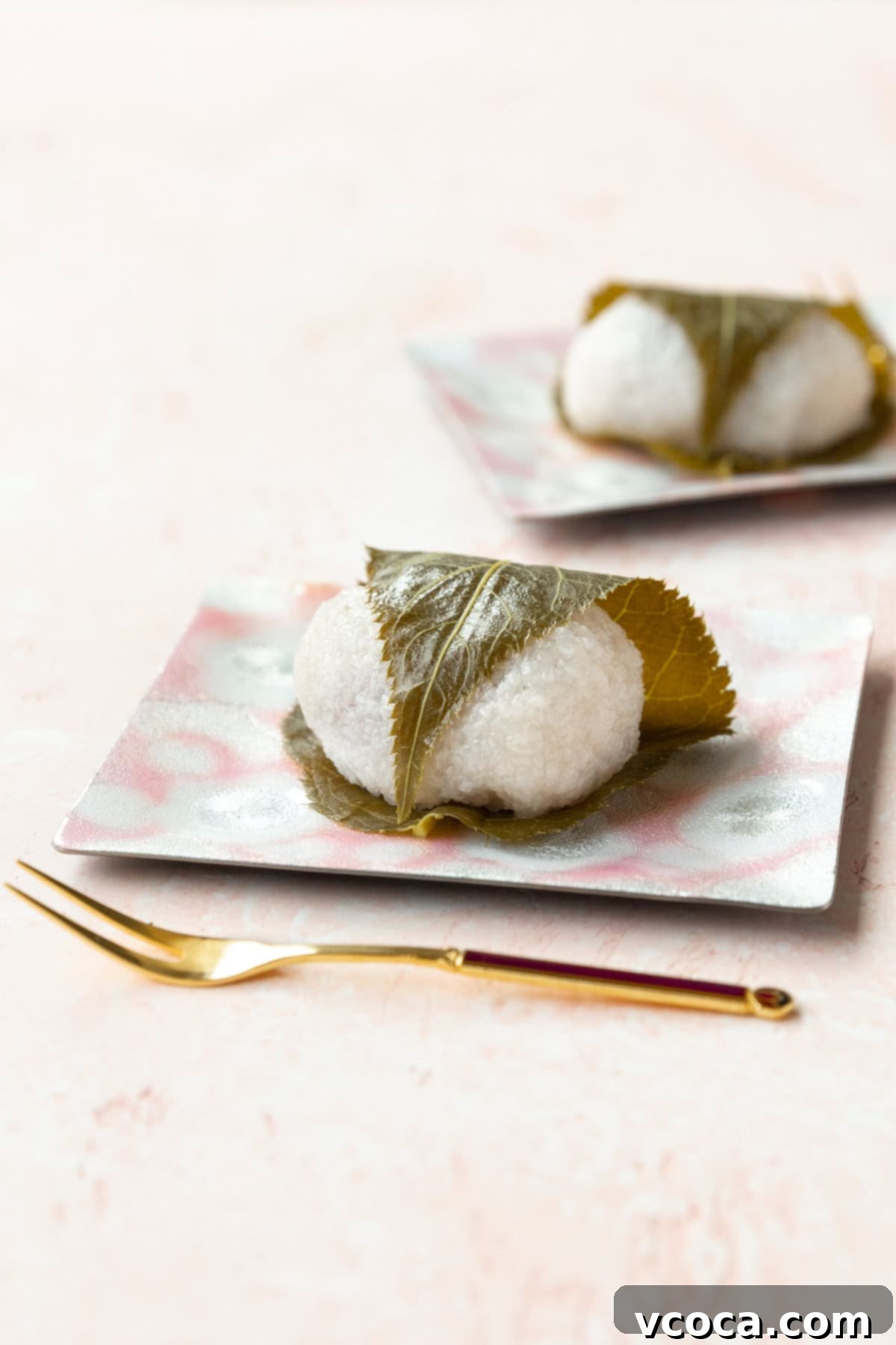 Sakura Mochi 2 Sakura mochi on a pink dessert plate on a pink surface. A sweet, traditional Japanese dessert for spring.