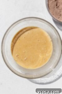Eggs, milk, sugar, oil, and butter mixed together in a bowl.