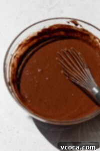 Gluten free chocolate cake batter in a bowl with a whisk.