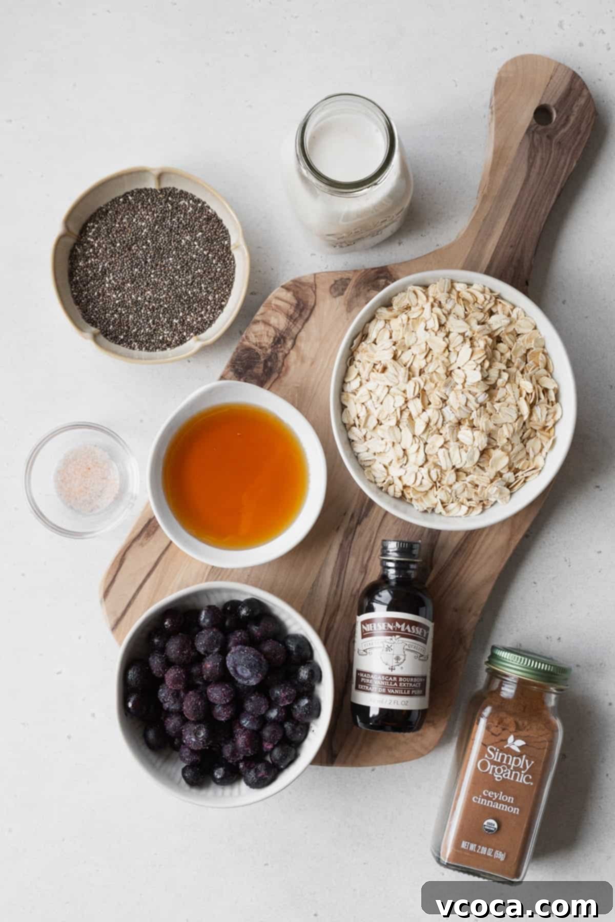 Effortless Blueberry Overnight Oats 3 Ingredients for blueberry overnight oats, including rolled oats, blueberries, almond milk, and maple syrup, perfectly measured in small bowls on a wooden surface.