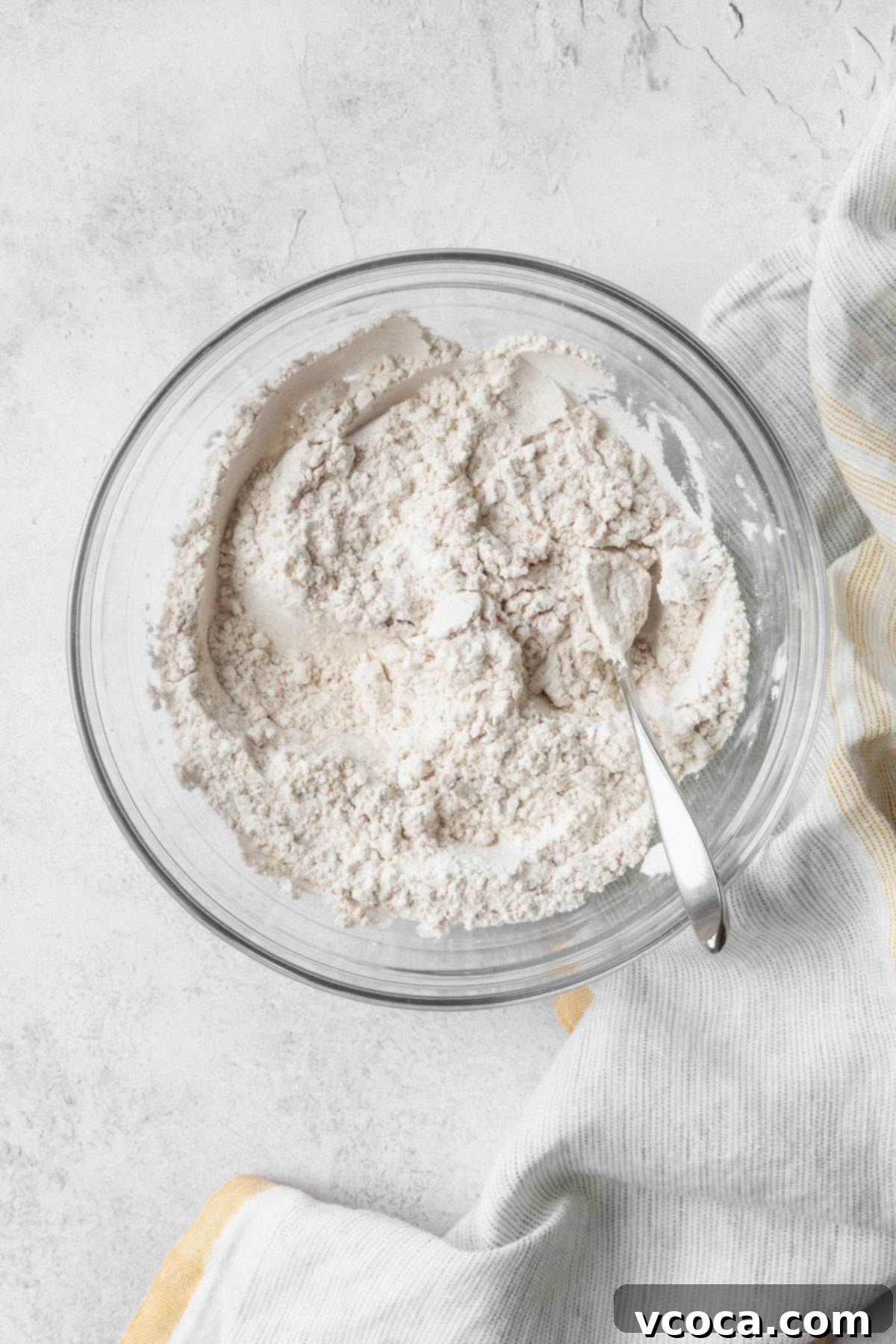 Gluten Free Zucchini Bread Delights 5 Dry ingredients in a glass bowl with a spoon, perfectly measured and ready to be mixed into the gluten-free zucchini bread batter.