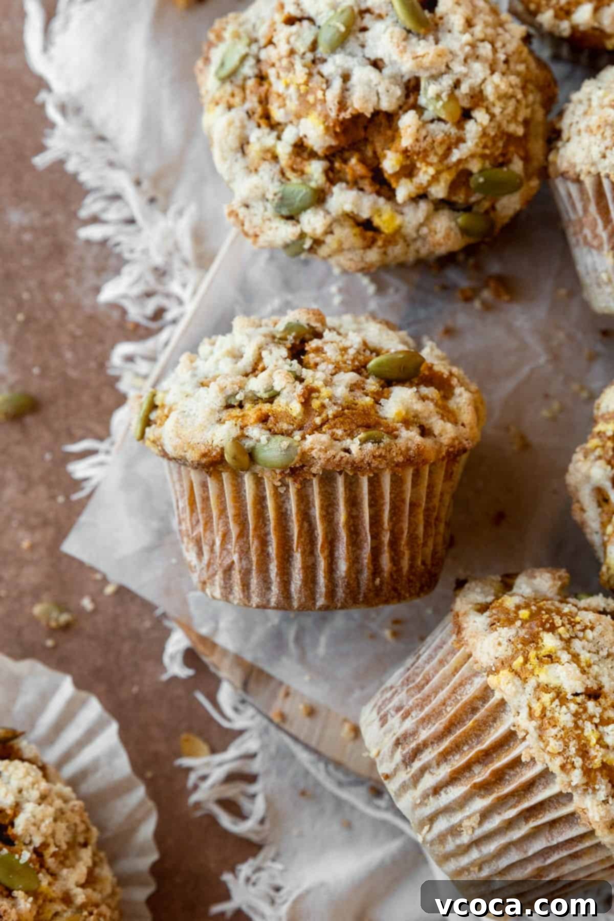 A pumpkin streusel muffin on its side with more muffins around it.