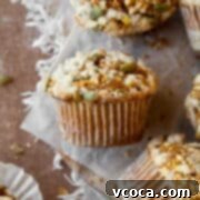 A gluten free pumpkin muffin with streusel topping and pumpkin seeds on a piece of parchment paper.