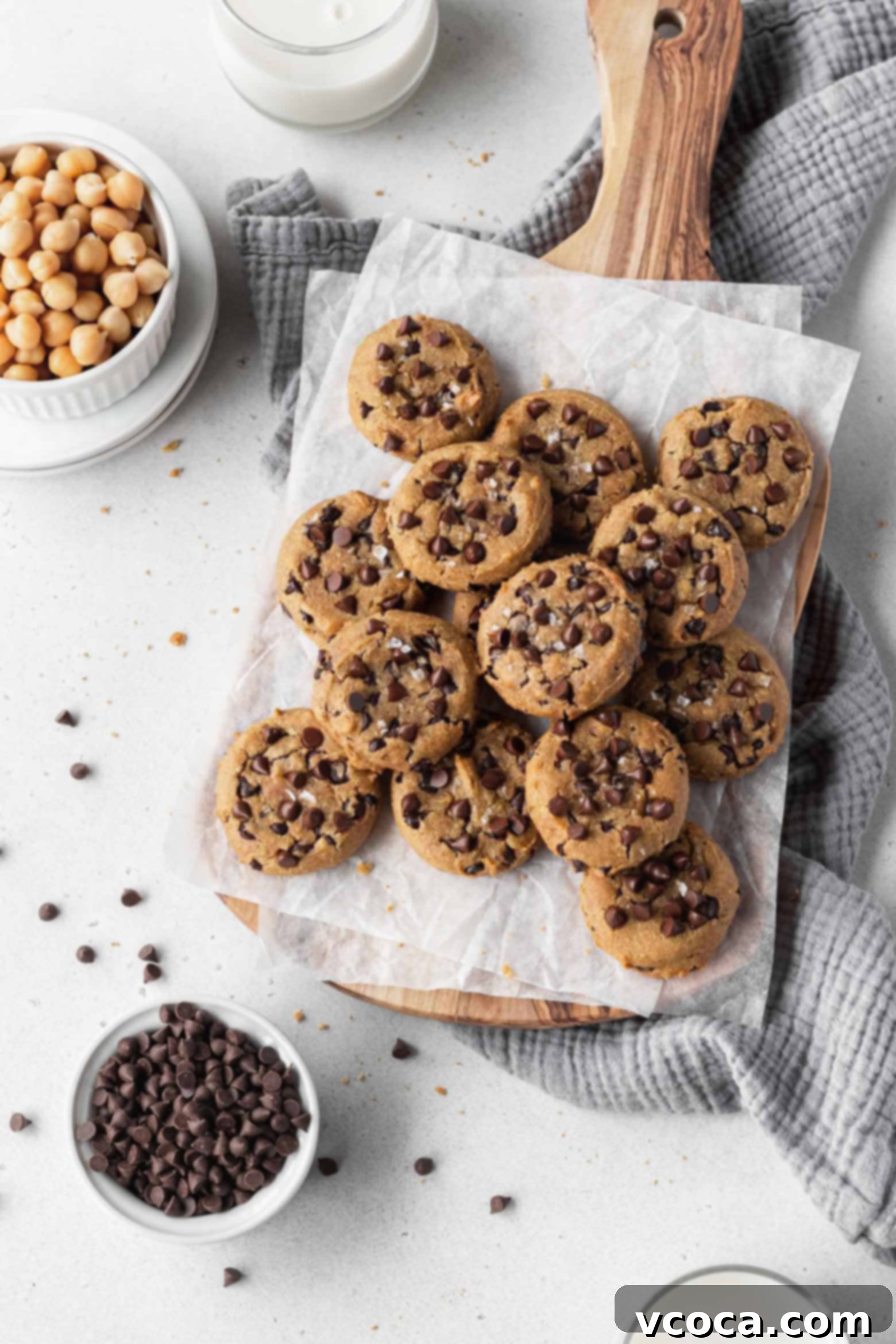 Freshly baked gluten-free chocolate chip chickpea cookies on parchment paper, cooling on a baking sheet.