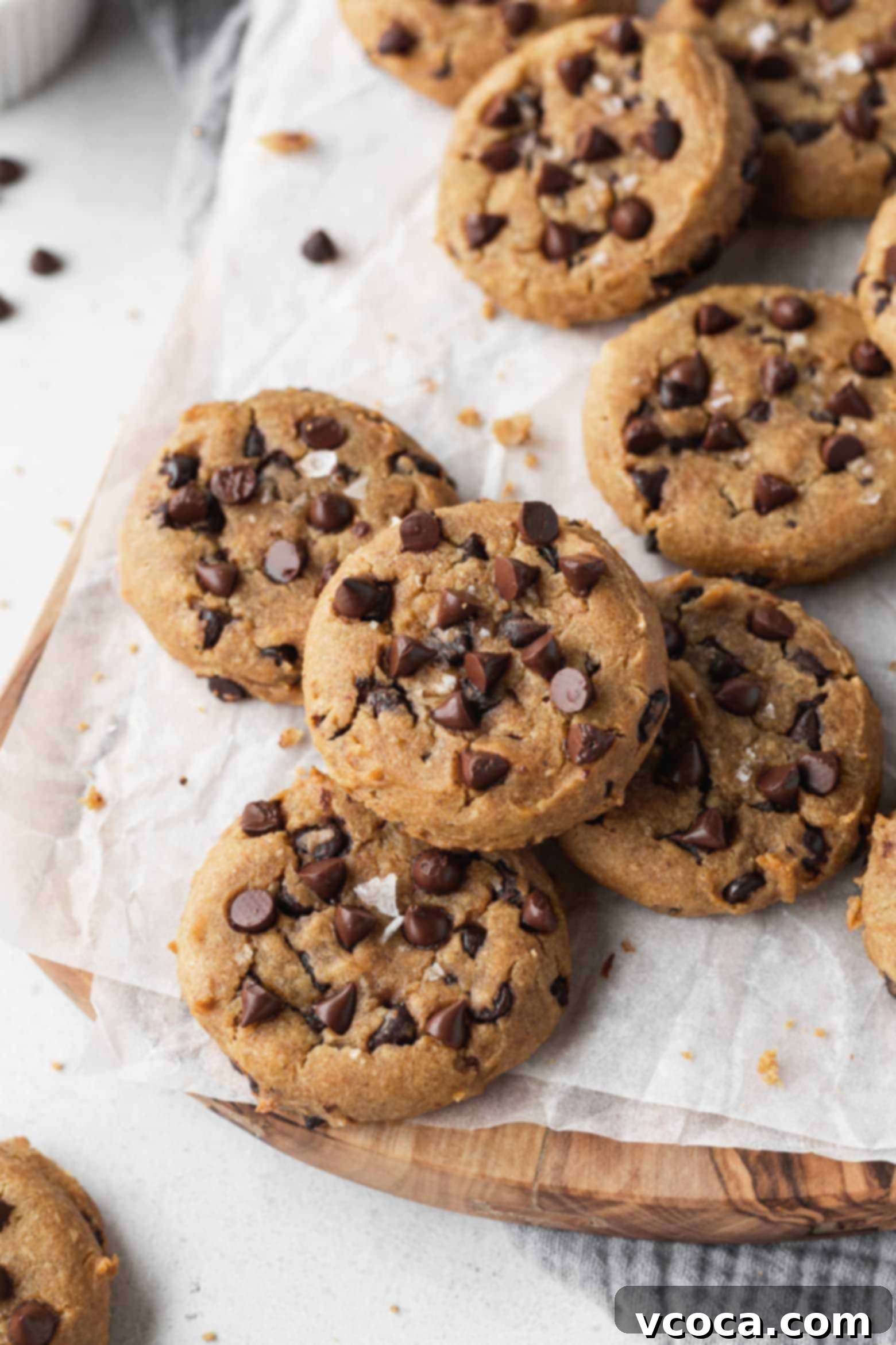 A collection of perfectly baked chocolate chip chickpea cookies arranged on a rustic wooden board, ready to be enjoyed.