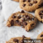 A close-up of a perfectly baked chocolate chip chickpea cookie, featuring melted chocolate chips and a golden-brown edge.
