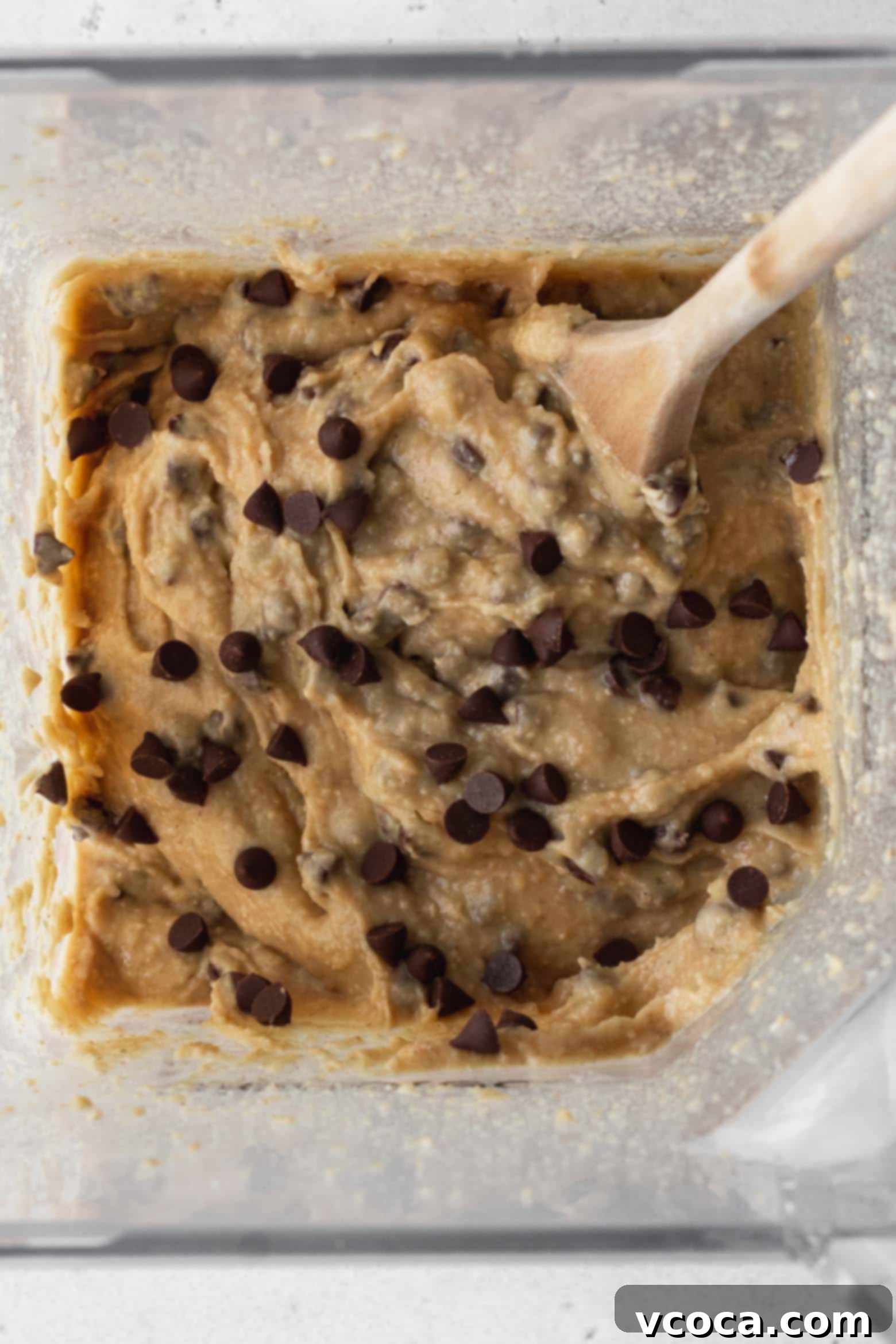 Chocolate chip chickpea cookie dough mixed with chocolate chips in a blender.