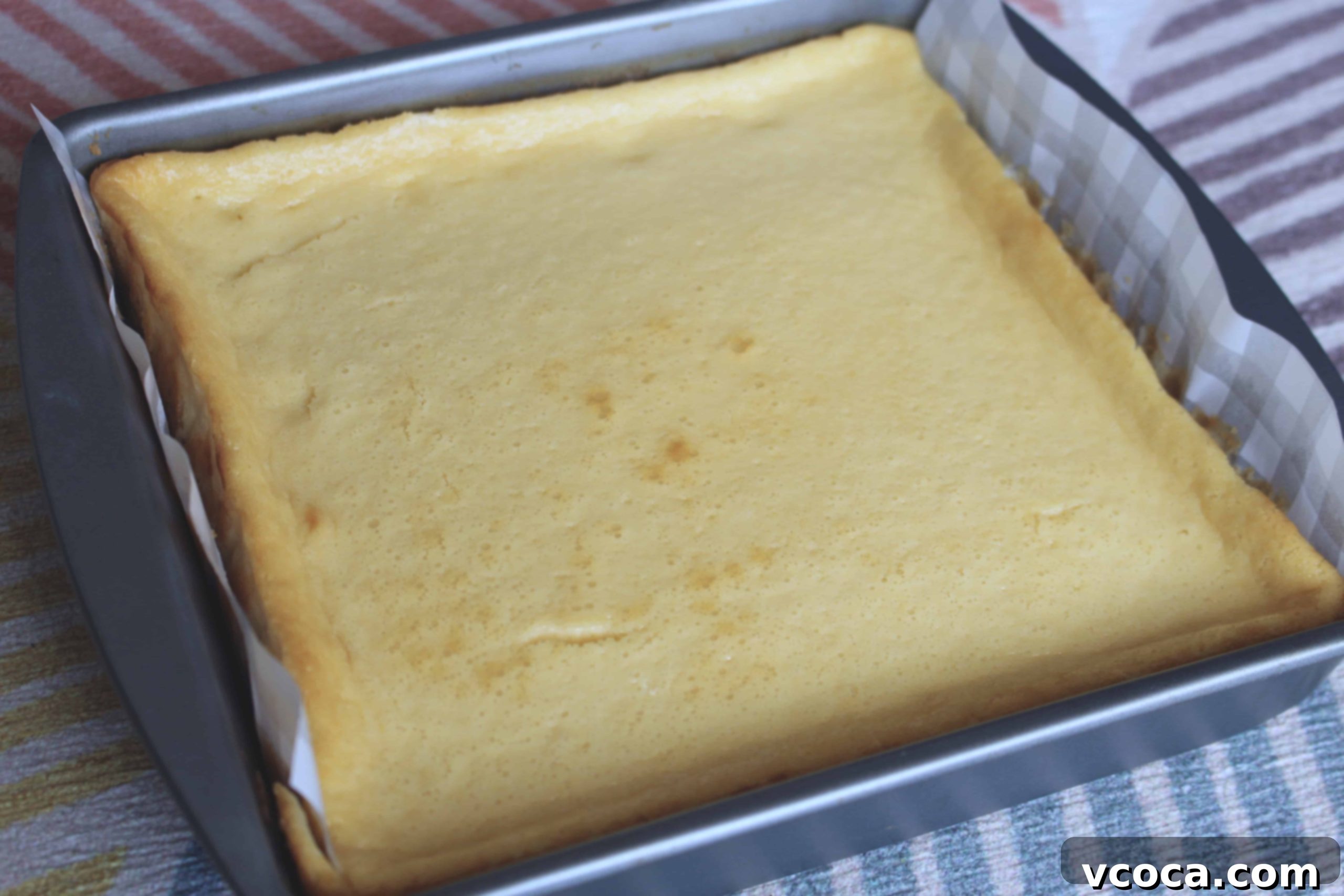 Freshly baked cheesecake bars, slightly puffed, cooling on a wire rack