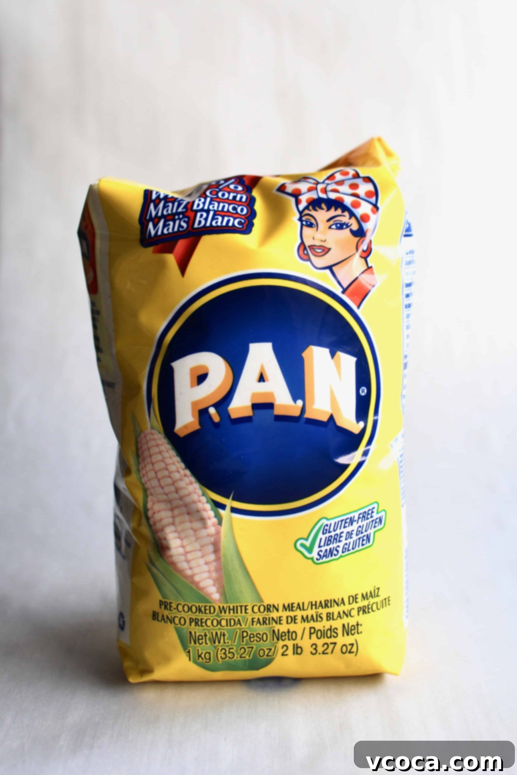 A vibrant yellow bag of Harina PAN, precooked cornmeal, sits prominently against a clean white backdrop, highlighting the essential ingredient for arepas.