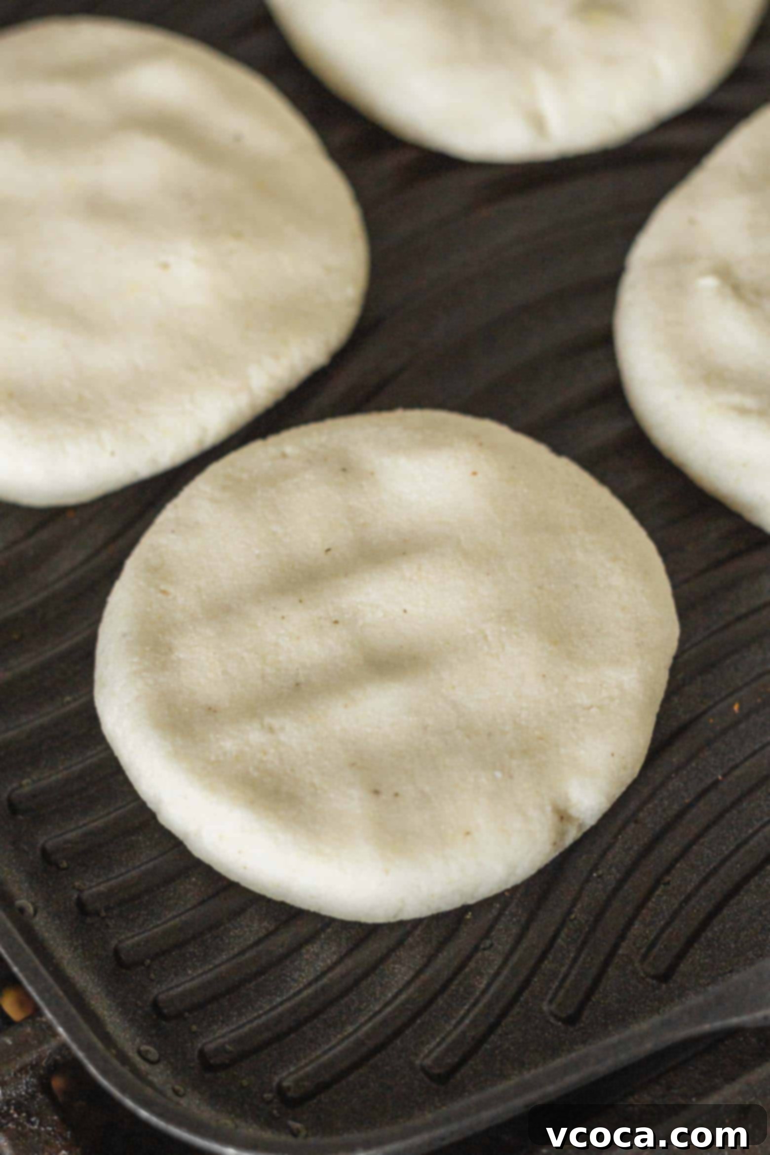 Reina Pepiada Venezuelan Arepas 8 Uncooked arepas neatly arranged on a grill, ready to be cooked