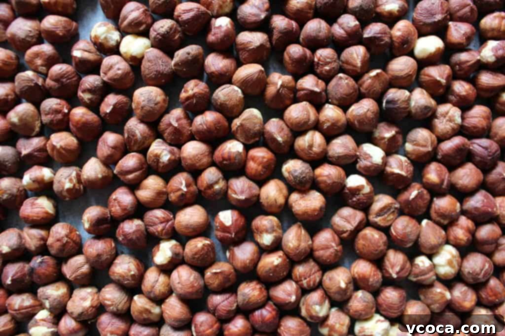 Close-up of raw hazelnuts spread on a baking sheet before roasting.