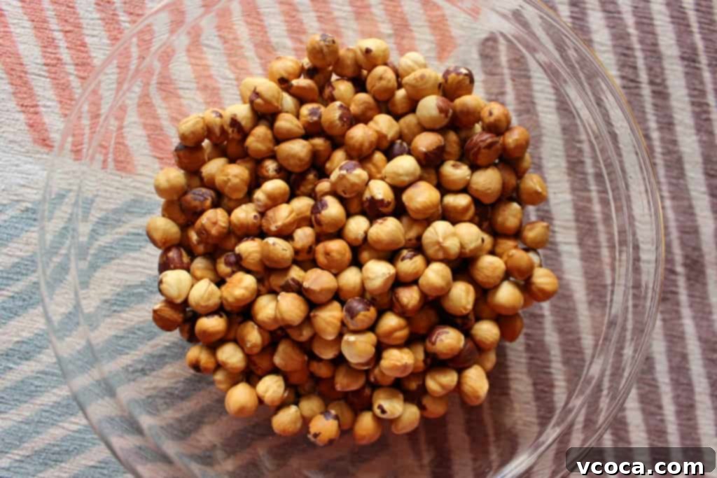 Hands vigorously rubbing roasted hazelnuts inside a tea towel to remove their skins.