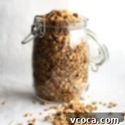 Seriously Delicious Gluten-Free Granola 8 A glass jar of gluten-free granola on a white surface with some spilled out.