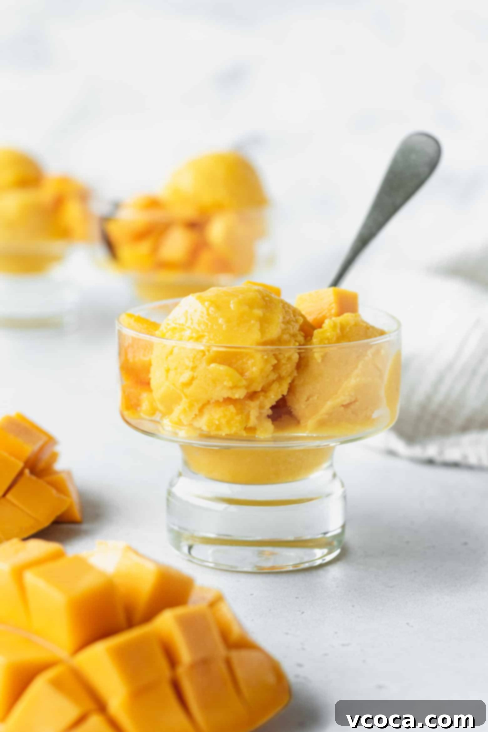 Easy Two Ingredient Mango Sorbet 2 Scoops of vibrant, golden mango lime sorbet in a elegant glass, garnished with fresh lime zest, ready to be enjoyed as a refreshing dessert