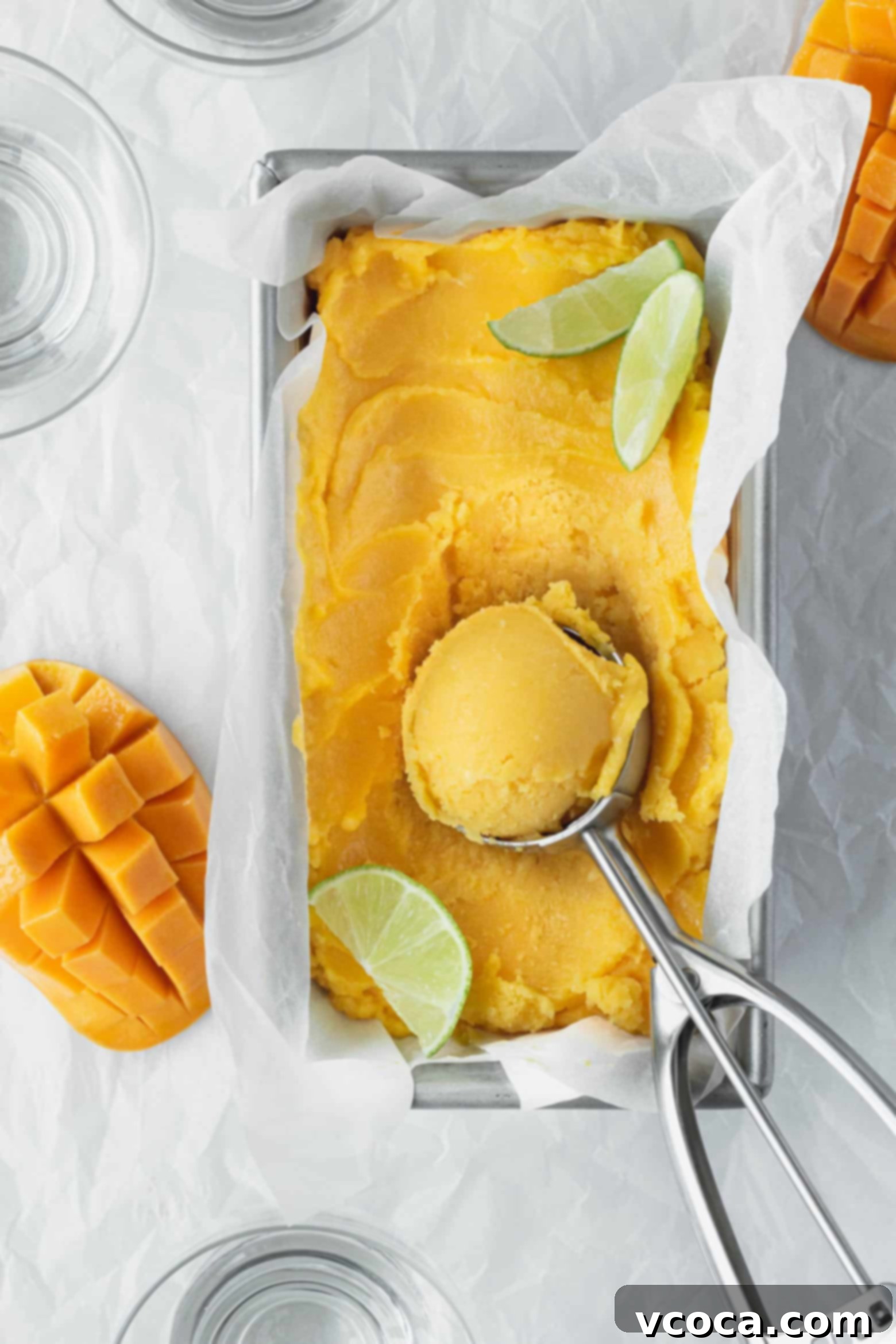 Easy Two Ingredient Mango Sorbet 6 Smooth and perfectly scooped mango lime sorbet resting in a shallow pan, with an ice cream scoop poised, ready for serving