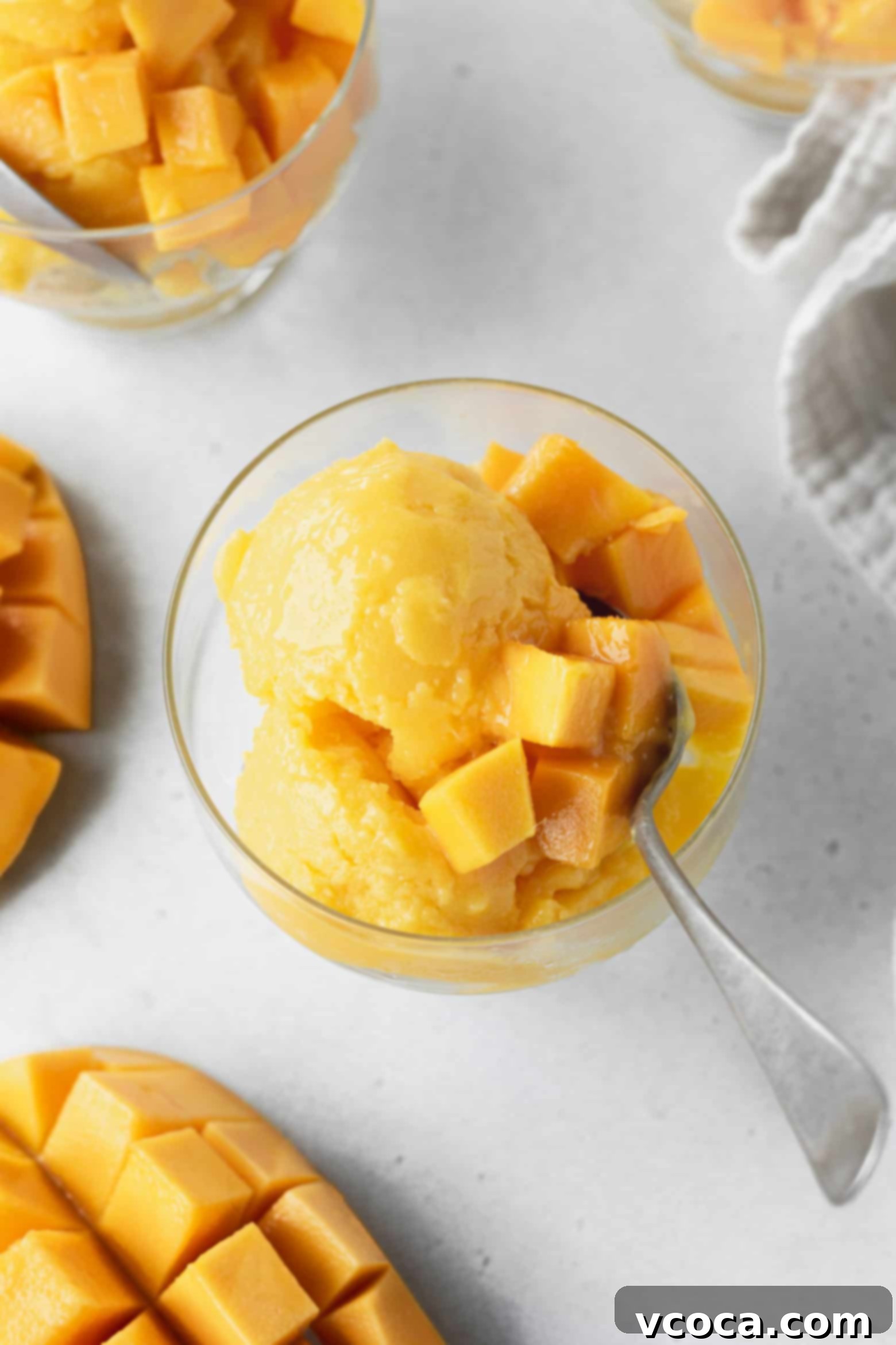 Easy Two Ingredient Mango Sorbet 8 Exquisite mango sorbetto served in a elegant glass, garnished with fresh mango chunks and delicate lime zest, perfect for a tropical treat