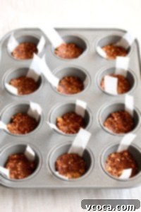 Vegan chocolate almond crust pressed into a mini muffin pan, ready for the filling.
