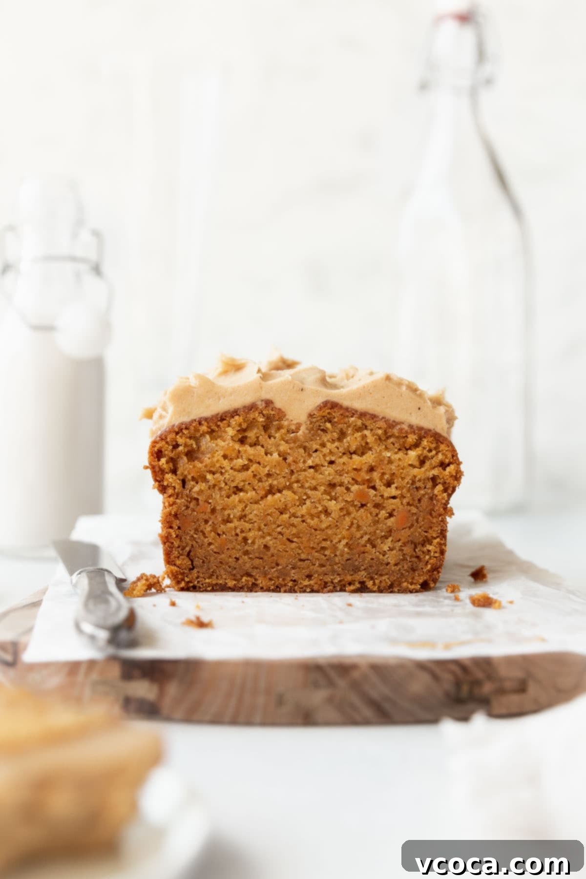 Spiced Sweet Potato Cake with Cashew Frosting 2 Straight on shot of sweet potato cake with cashew frosting on parchment paper over a wooden board.