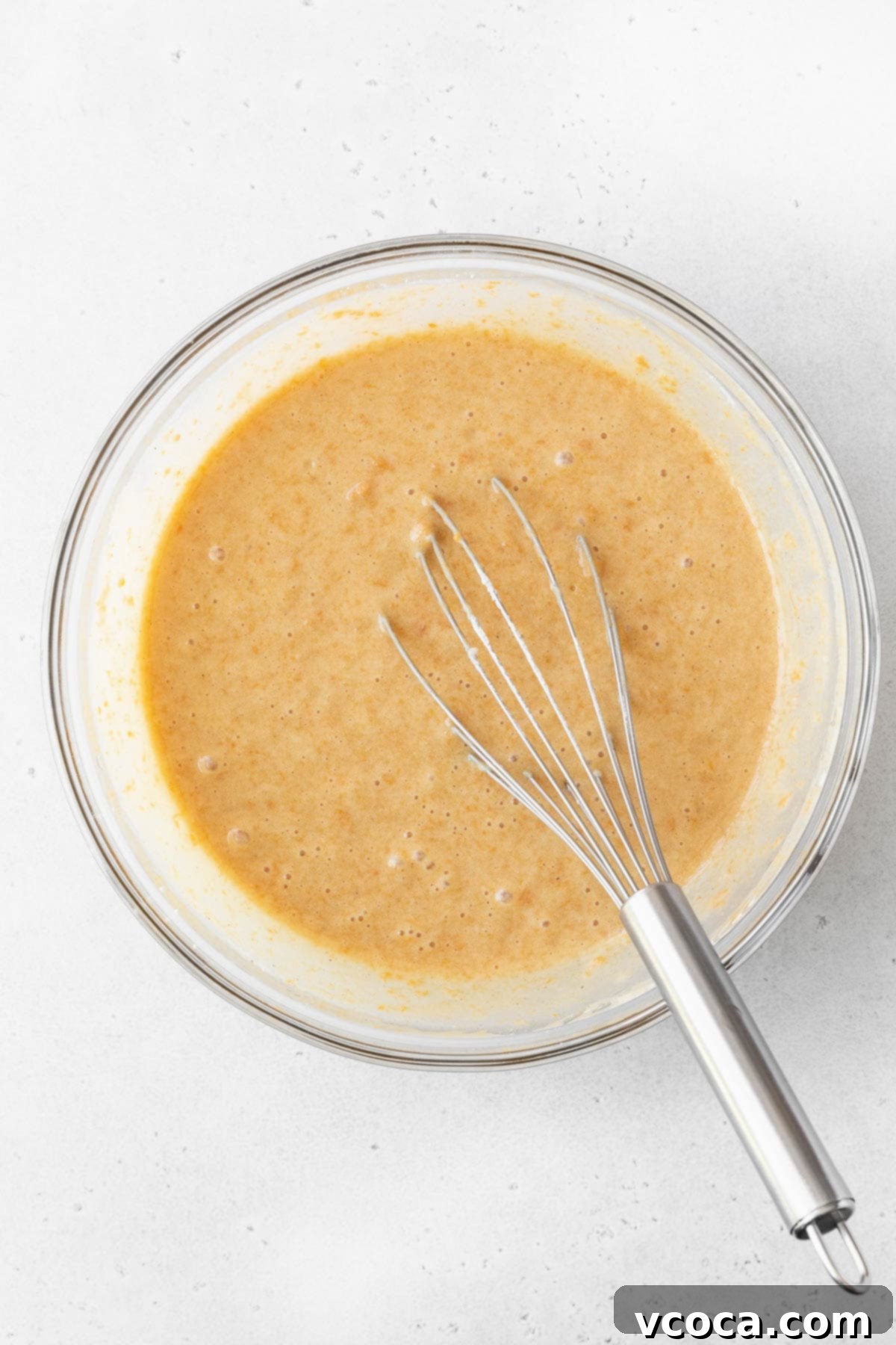 Spiced Sweet Potato Cake with Cashew Frosting 12 Healthy sweet potato cake batter in a glass bowl with a silver whisk.