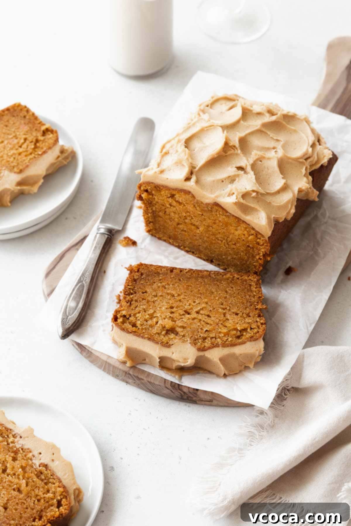 Spiced Sweet Potato Cake with Cashew Frosting 3 A sliced loaf of gluten-free sweet potato cake with maple frosting with a silver knife next to it.