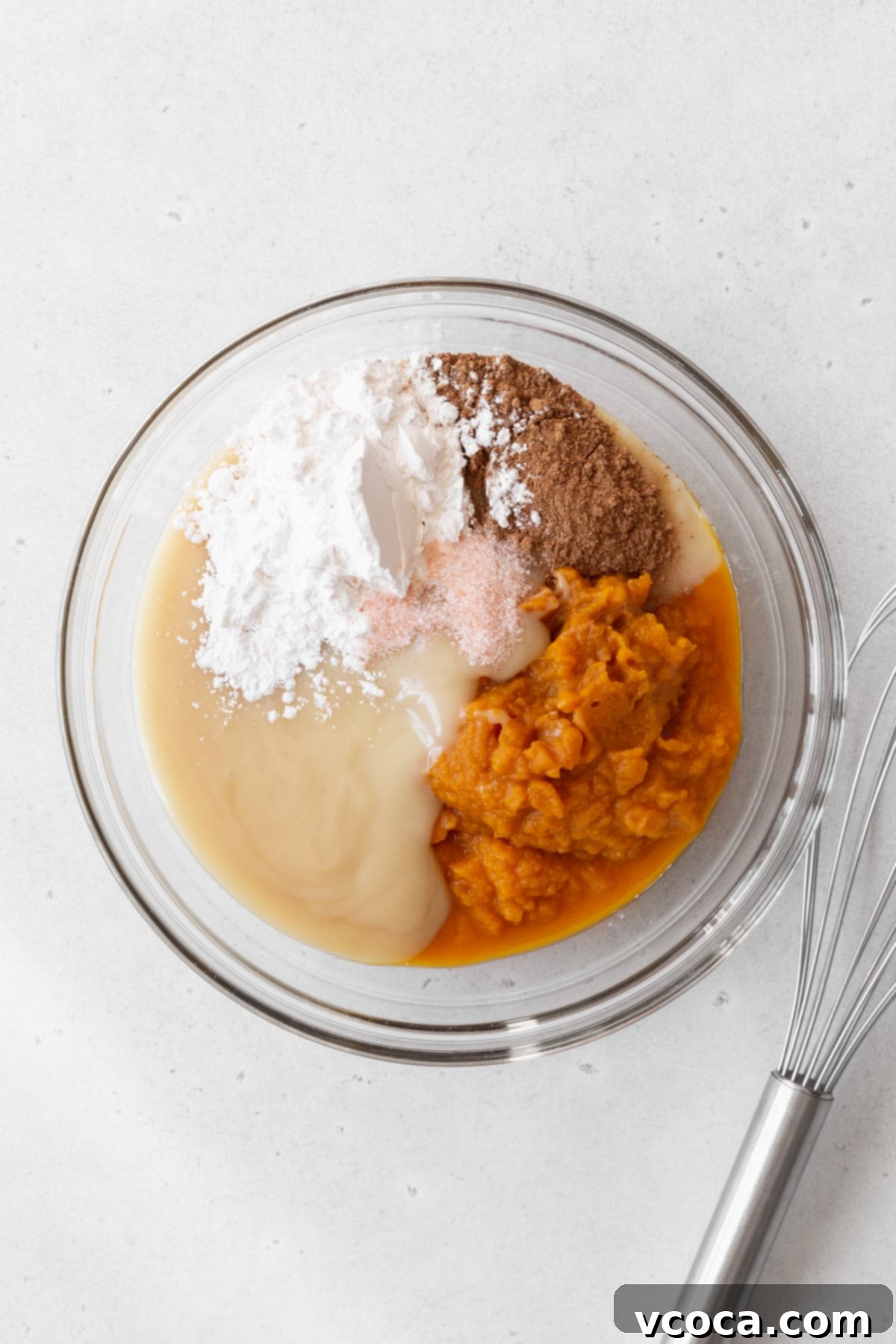 Decadent Vegan Pumpkin Pie 6 Pumpkin pie filling ingredients in a glass bowl next to a wire whisk.