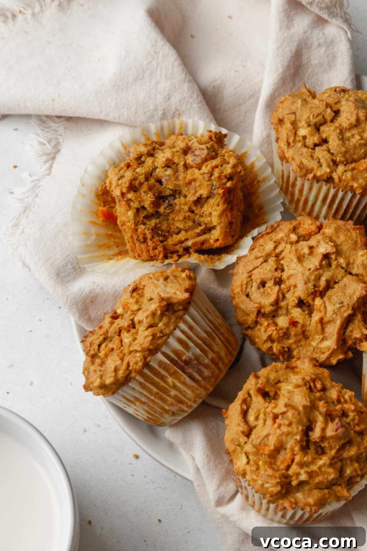 Vibrant Morning Glory Muffins Healthy Gluten Free 14 An overhead shot of a pile of golden-brown morning glory muffins, with one muffin turned on its side to reveal its moist, dense, and fruit-and-nut-flecked interior.
