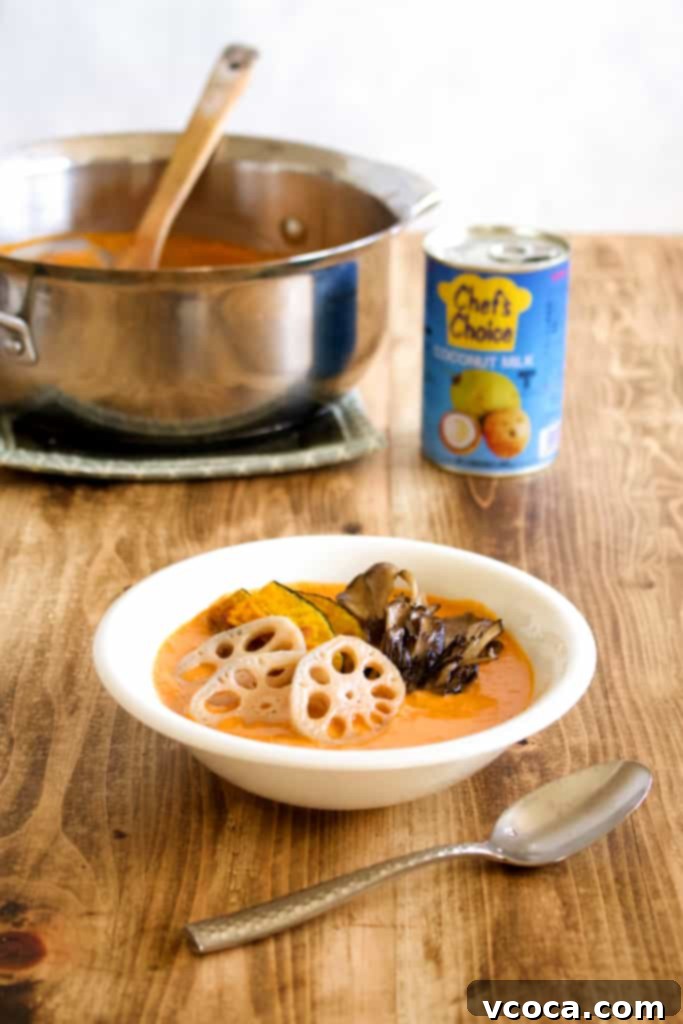A bowl of vegan coconut curry served with rice, showcasing the vibrant colors of kabocha squash, lotus root, and maitake mushrooms in a rich, creamy sauce. A healthy, delicious, and warming plant-based meal.