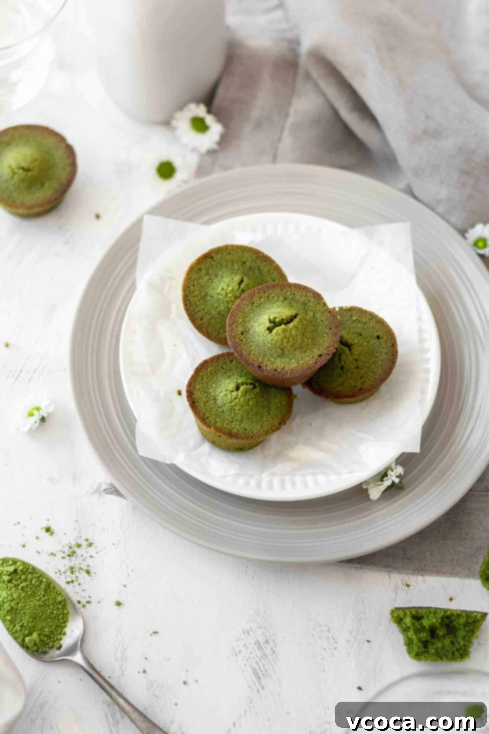 Matcha almond cake bites 2 Matcha financiers on a plate, showcasing their elegant green hue and golden edges.