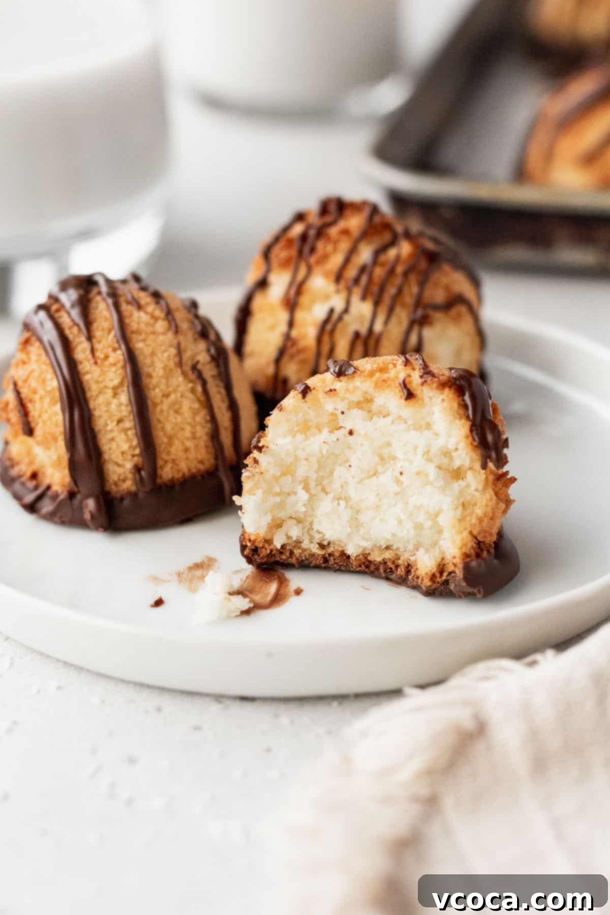 Heavenly Vegan Coconut Macaroons 12 3 gluten free vegan macaroons on a white plate with one with a bite taken out of it.