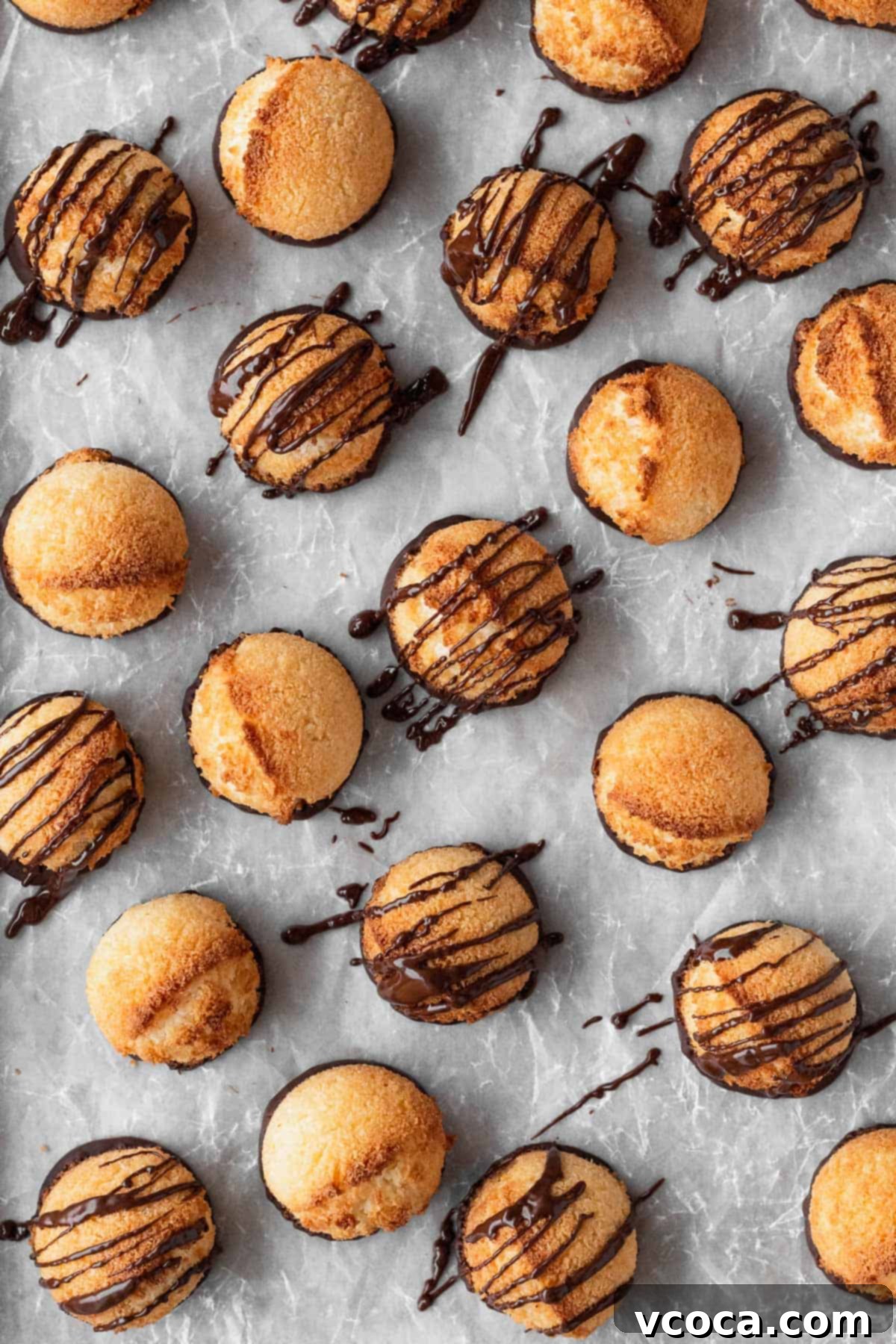 Heavenly Vegan Coconut Macaroons 9 Vegan coconut macaroons with a chocolate drizzle on parchment paper.