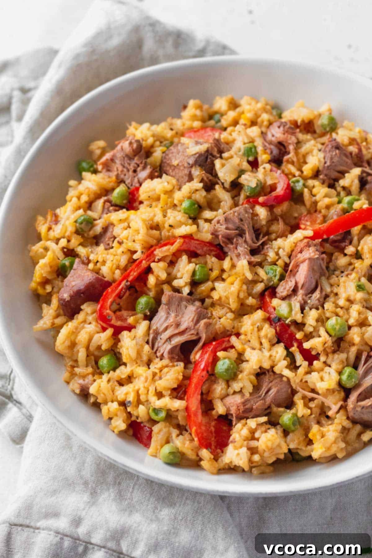 Flavorful Vegan Arroz Valenciana 12 A large, inviting bowl of vegan Filipino rice, Arroz Valenciana, garnished with sliced red bell peppers and green peas, ready to be enjoyed.