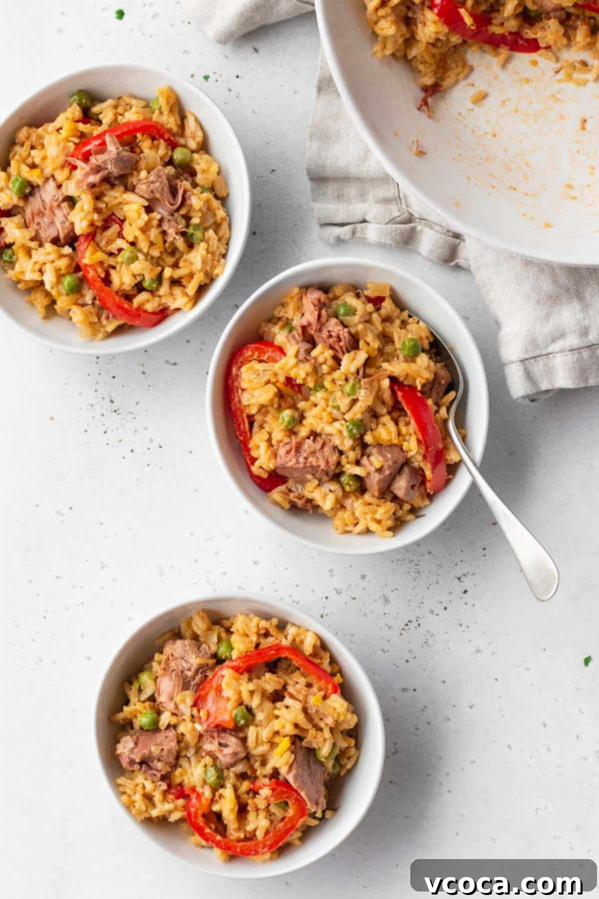 Flavorful Vegan Arroz Valenciana 13 Three perfectly portioned bowls of vegan Arroz a la Valenciana are elegantly presented on a white table, inviting diners to enjoy.