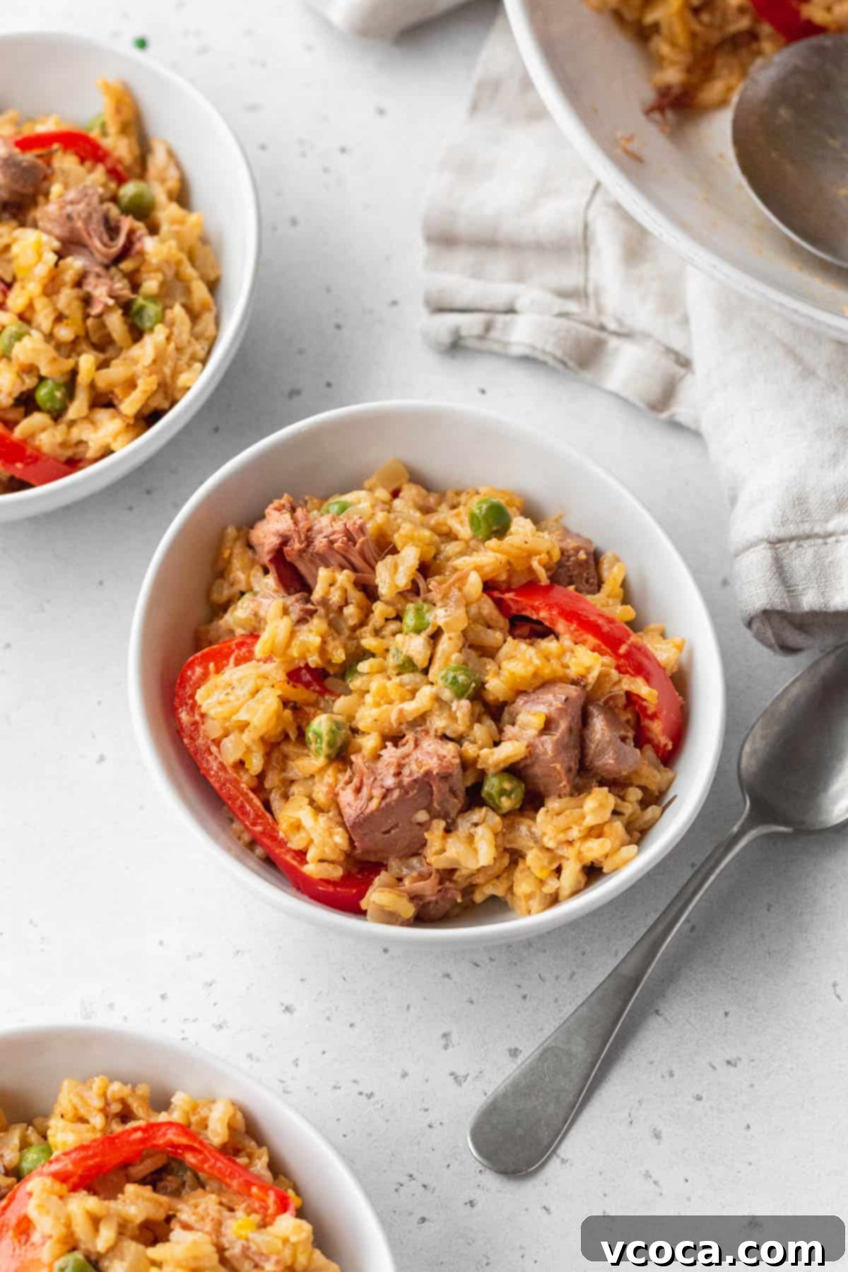 Flavorful Vegan Arroz Valenciana 3 Three small bowls of vegan Arroz a la Valenciana artfully arranged on a clean white surface, highlighting its vibrant colors and inviting texture.