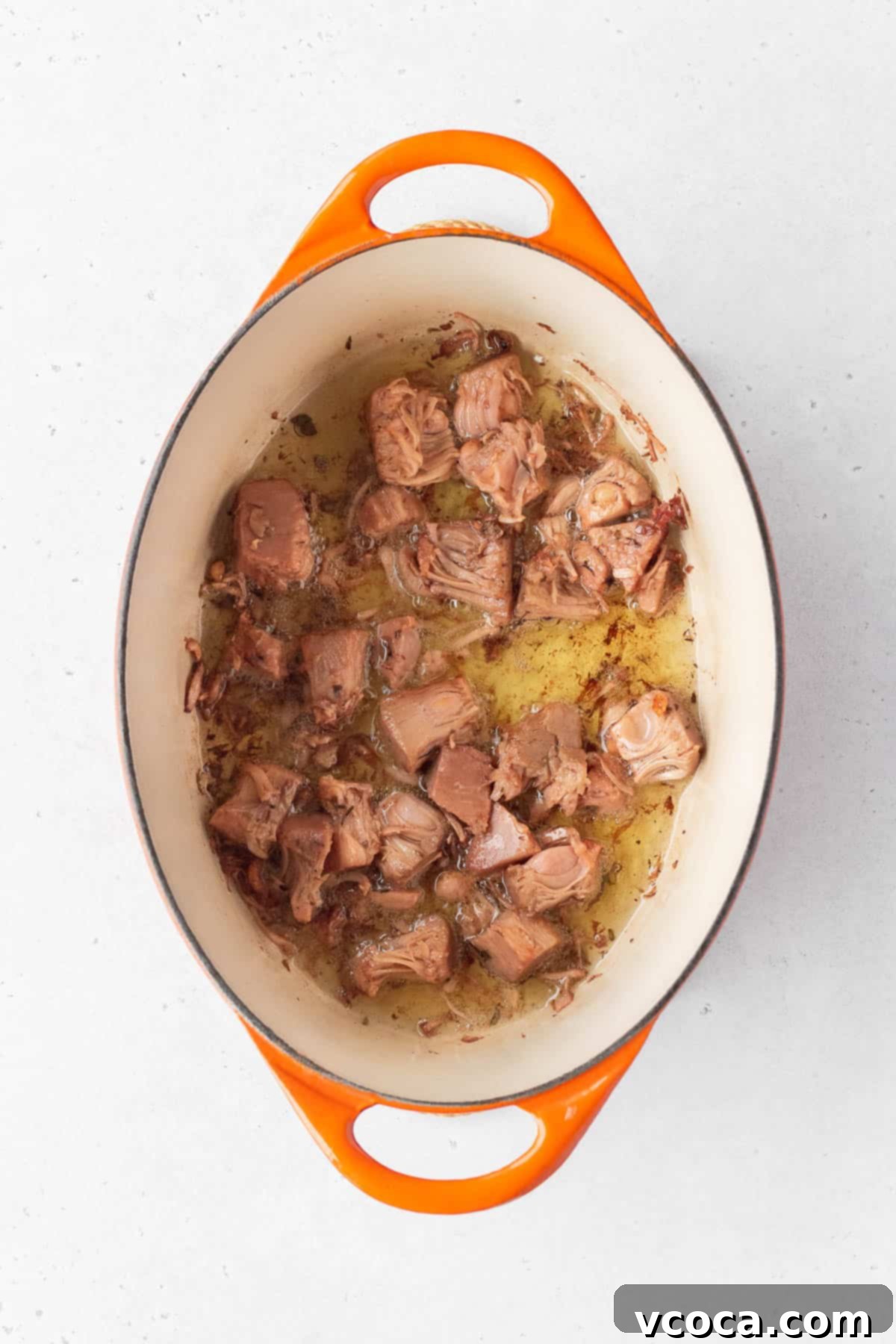 Flavorful Vegan Arroz Valenciana 5 Young green jackfruit confit being cooked and crisped in oil in a heavy-bottom pot.