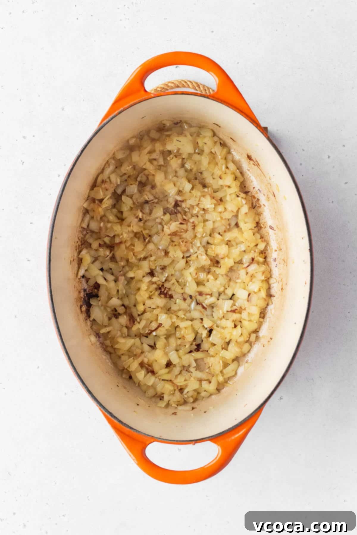 Flavorful Vegan Arroz Valenciana 6 Minced onion and garlic being expertly cooked in a large enameled pot, forming the aromatic base of the dish.