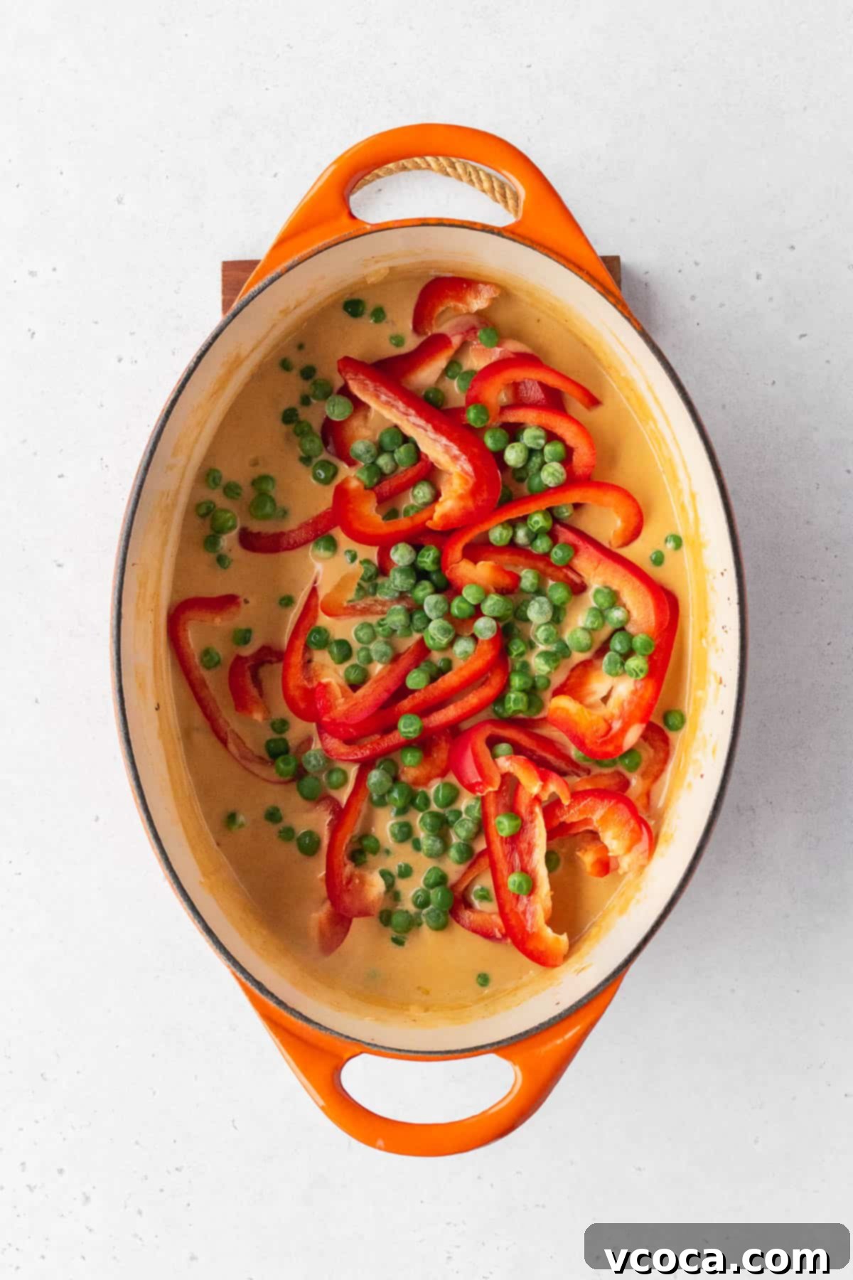 Flavorful Vegan Arroz Valenciana 9 Vibrant frozen peas and precisely sliced red bell peppers are carefully added to the pot of simmering rice.