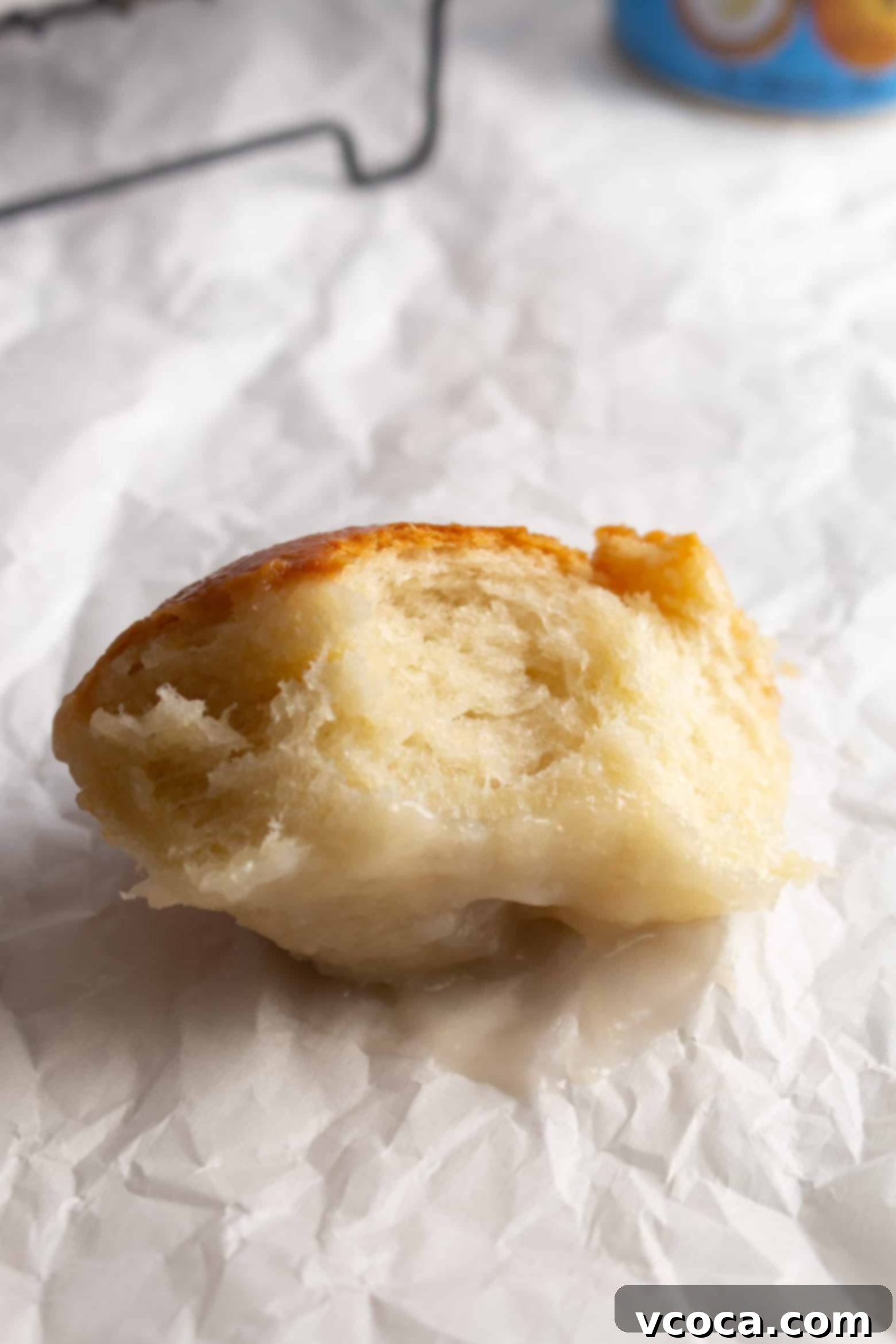 Pani Popo Samoan Sweet Coconut Buns 12 A bitten Pani Popo roll, showing its soft, fluffy interior.