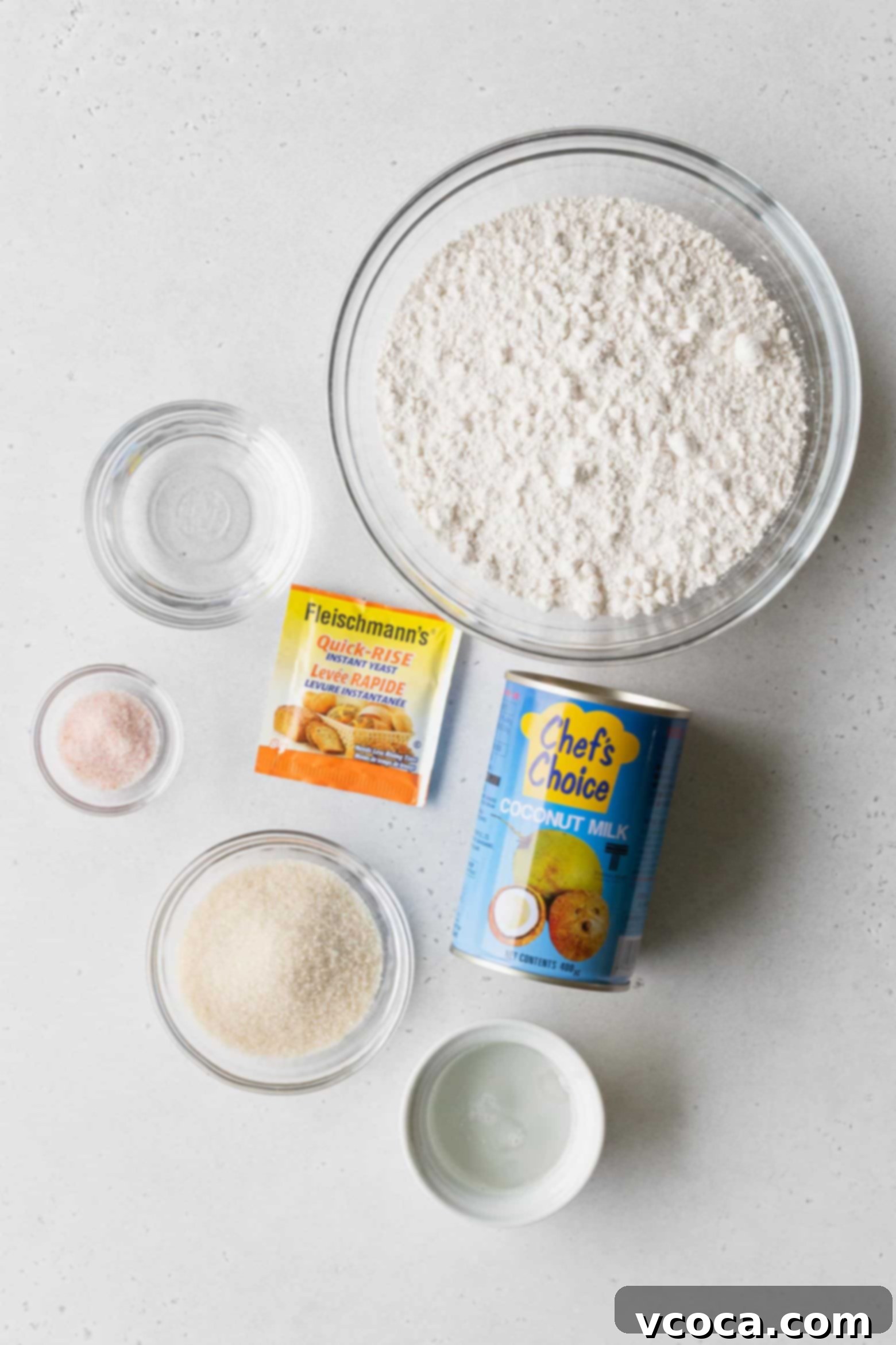 Pani Popo Samoan Sweet Coconut Buns 3 Ingredients for Pani Popo, including yeast, flour, coconut oil, and coconut milk, neatly arranged in bowls.