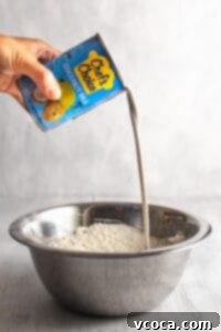 Pouring a can of coconut milk into a bowl with dry ingredients
