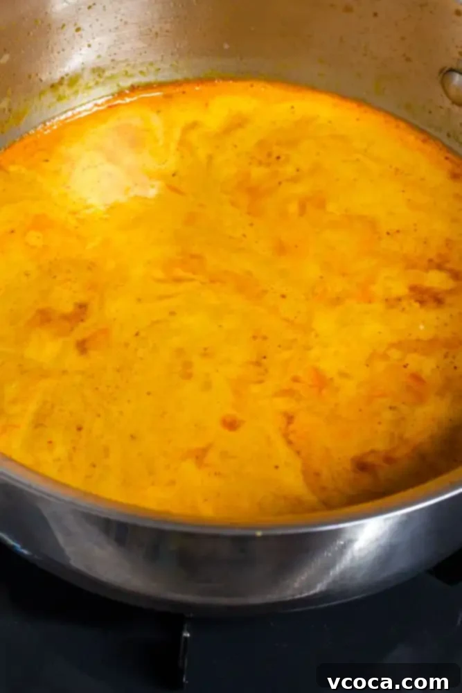 Quick and Easy Vegan Thai Red Curry Ramen 6 Coconut milk being stirred into sautéed red curry paste, creating a creamy base.