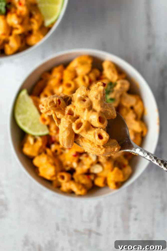 One Pot Vegan Red Curry Mac and Cheese 9 A serving of creamy vegan red curry mac and cheese in a bowl, garnished with fresh cilantro and a lime wedge, ready to be enjoyed.