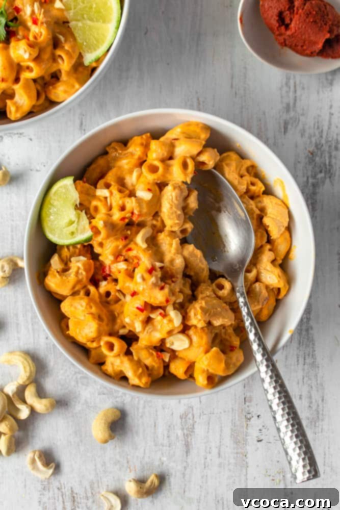 One Pot Vegan Red Curry Mac and Cheese 10 A bowl of vegan red curry mac and cheese garnished with fresh cilantro, roasted peanuts, and a lime wedge, highlighting the optional toppings.