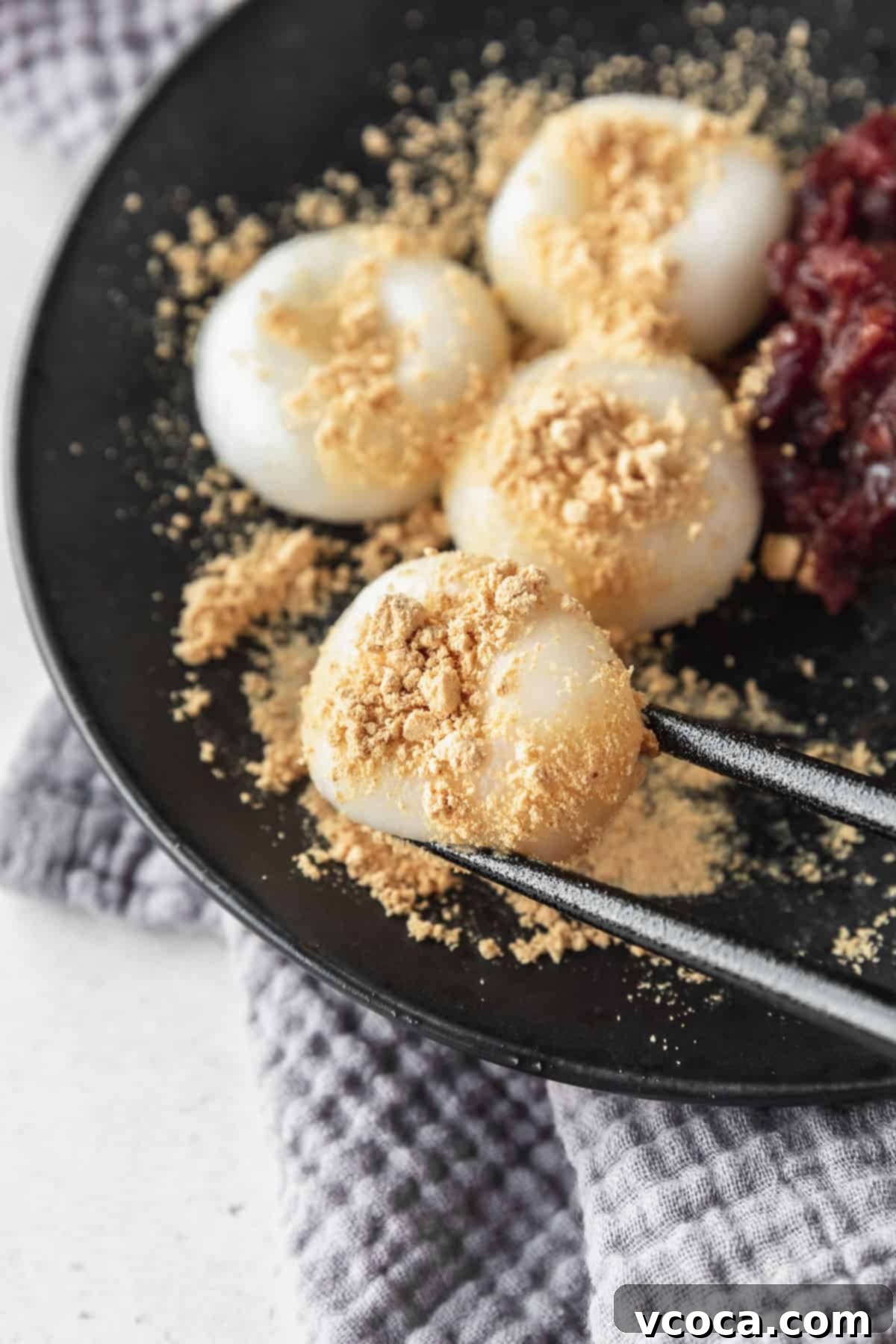 Pearl Rice Dumplings 14 Black chopsticks picking up a shiratama dango with kinako powder on top.