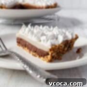 A slice of chocolate haupia pie on a white plate with a silver spoon, showing the perfectly layered dessert.