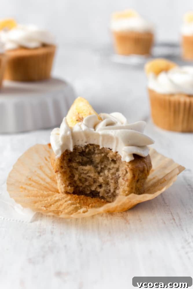 A banana cupcake, bitten to reveal its moist, fluffy interior, inviting a taste.