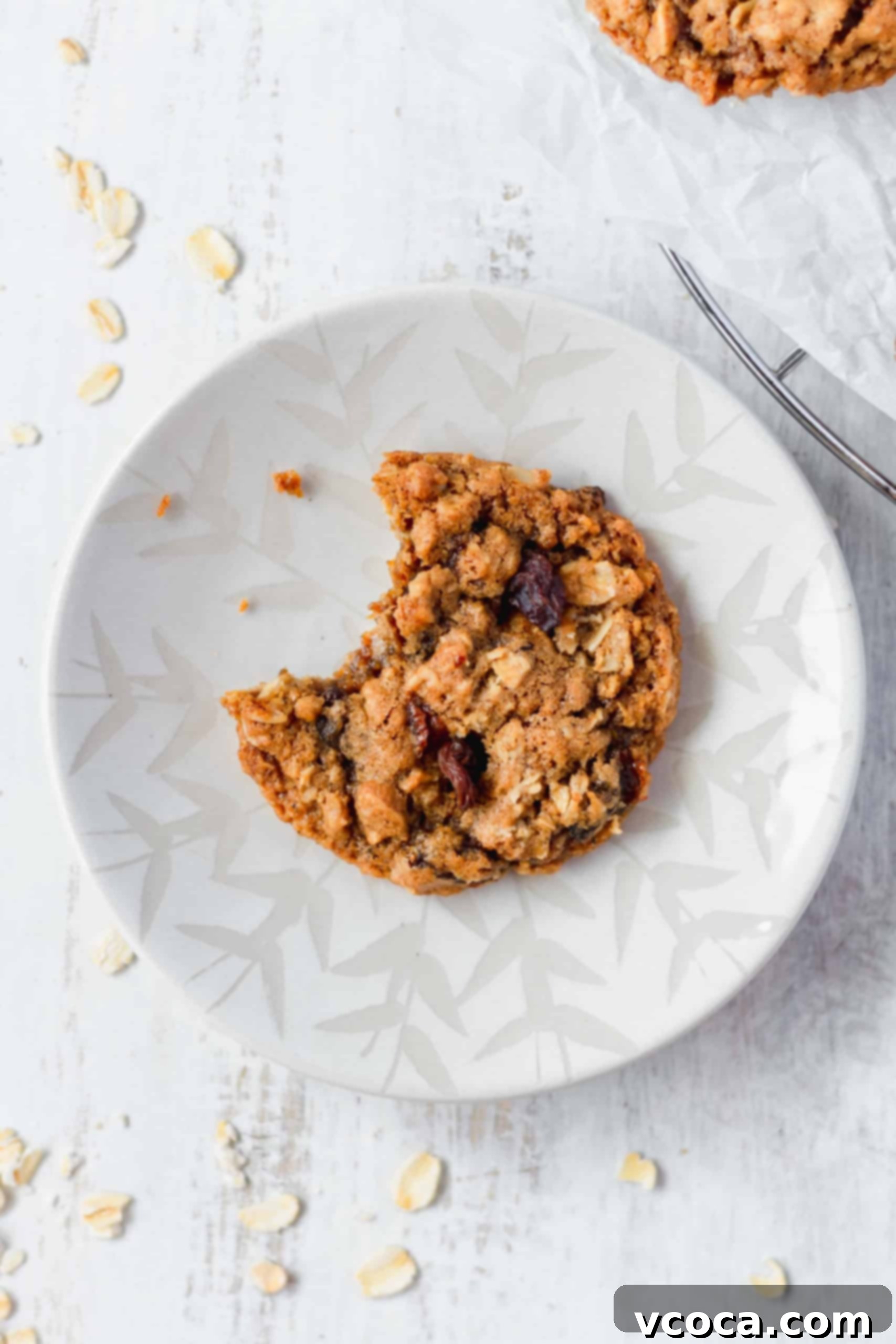 Chewy Brown Butter Oatmeal Raisin Cookies 7 A perfectly baked oatmeal raisin cookie with a bite taken out, resting on a white plate
