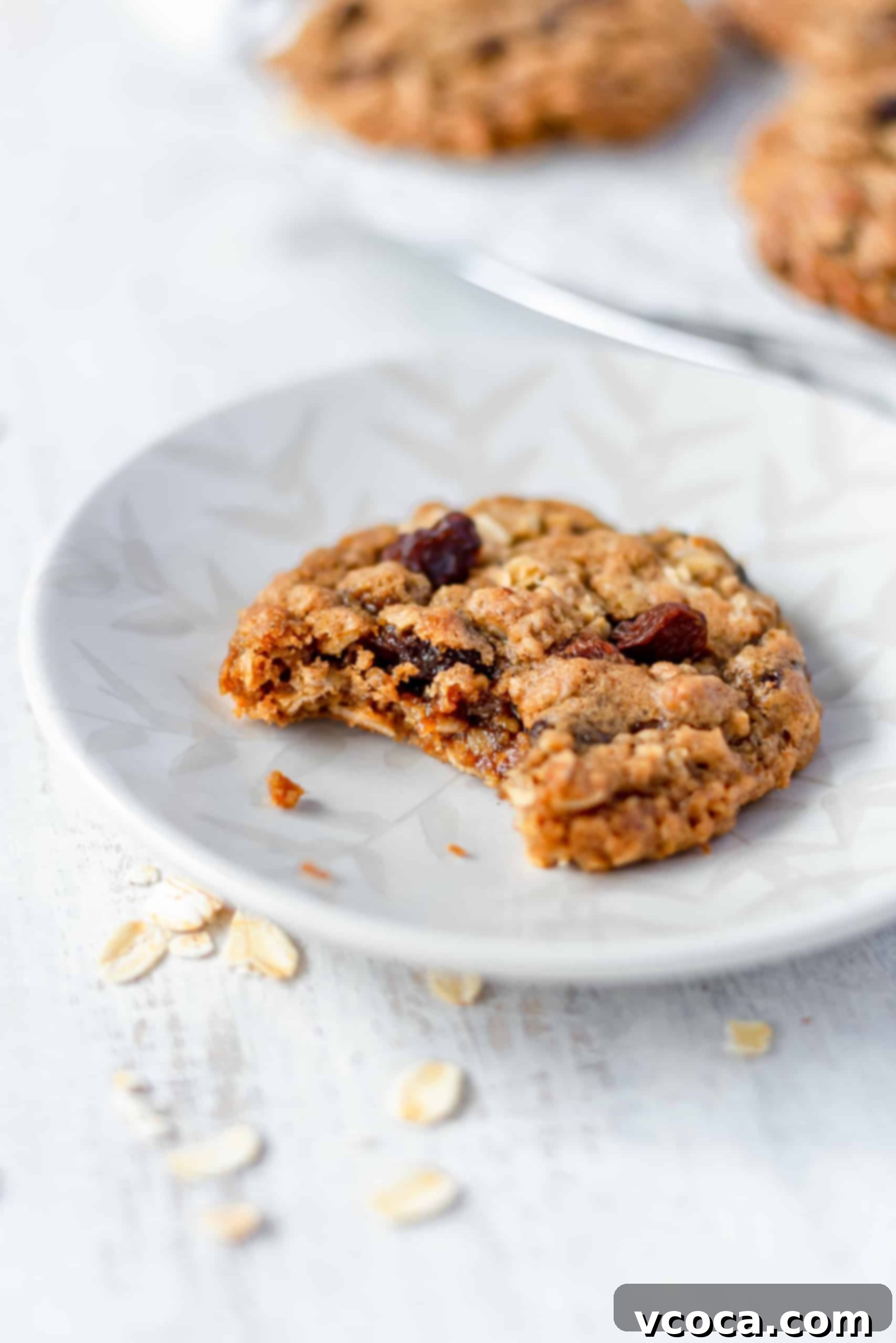 Chewy Brown Butter Oatmeal Raisin Cookies 8 A close-up of a bitten oatmeal raisin cookie on a plate, highlighting its soft interior