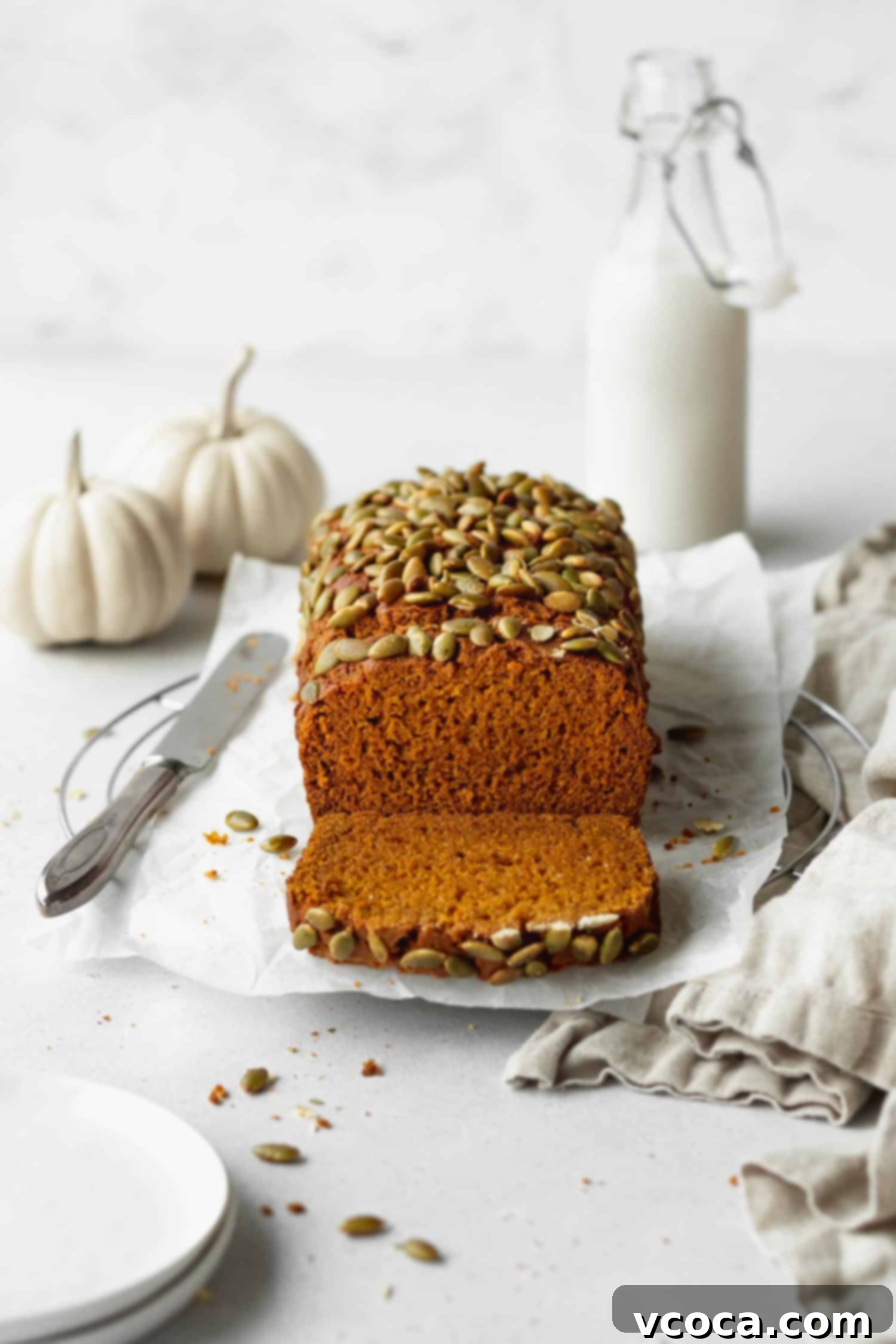 A freshly baked, beautifully domed loaf of gluten-free pumpkin bread, golden brown and topped with crunchy pepitas.