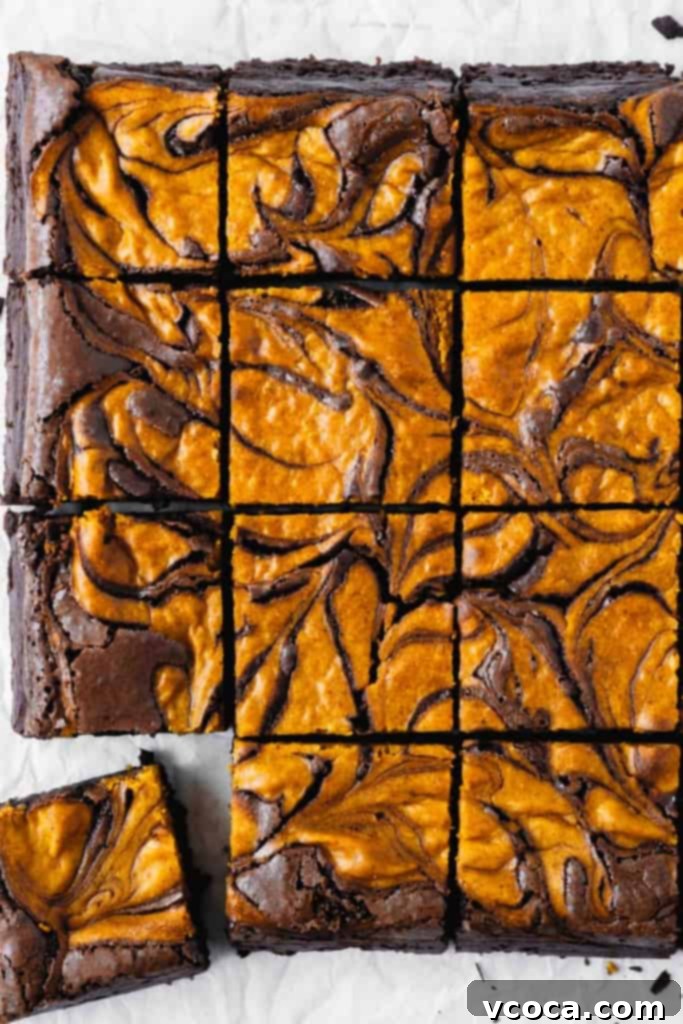 Swirled Pumpkin Cheesecake Brownies 3 Close up of a brownie with a distinct pumpkin cheesecake swirl, ready to be enjoyed.